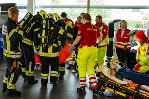 Rettungskräfte versorgen eine Person auf einer Trage in einem Innenraum.