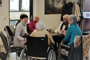 Sechs Frauen sitzen in einem Café und unterhalten sich gemütlich.