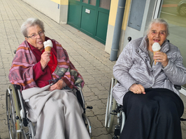 Drei Frauen genießen Eiscreme im Freien, eine in einem Rollstuhl.