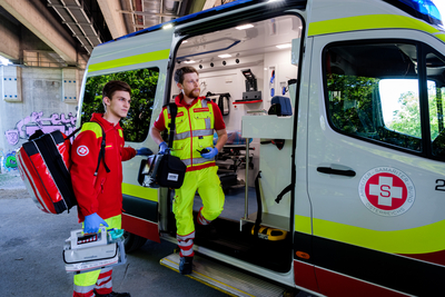 Zwei Rettungssanitäter bereiten sich vor, um in einen Krankenwagen einzusteigen.