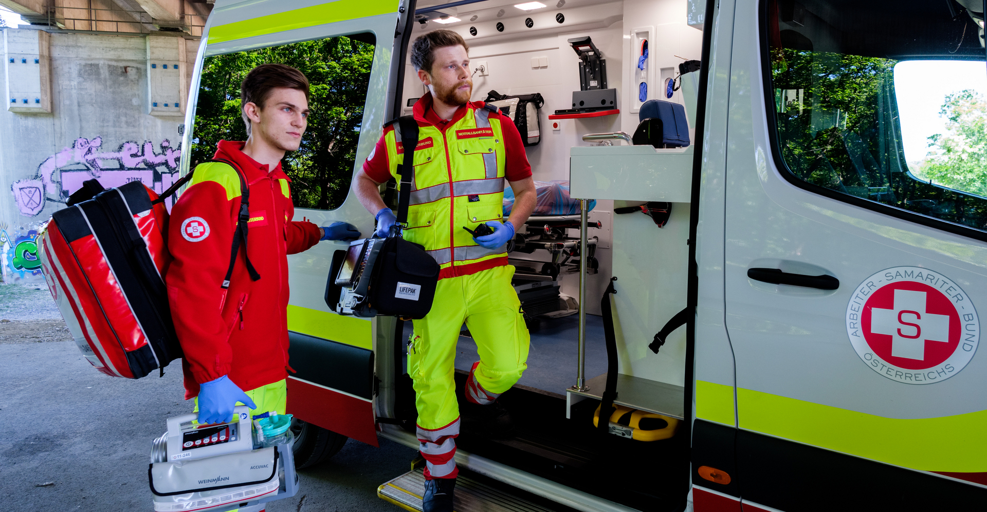 Zwei Rettungssanitäter bereiten sich vor, um in einen Krankenwagen einzusteigen.