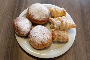 Ein Teller mit drei Puddingkugeln und zwei gefüllten Teigstücken.