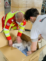 Zwei Personen packen FFP3-Masken aus einem Karton aus.