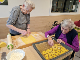 Zwei ältere Frauen backen gemeinsam Teig und formen einige Kekse.