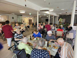 Ältere Menschen sitzen in einem Speisesaal und genießen gemeinsam eine Mahlzeit.