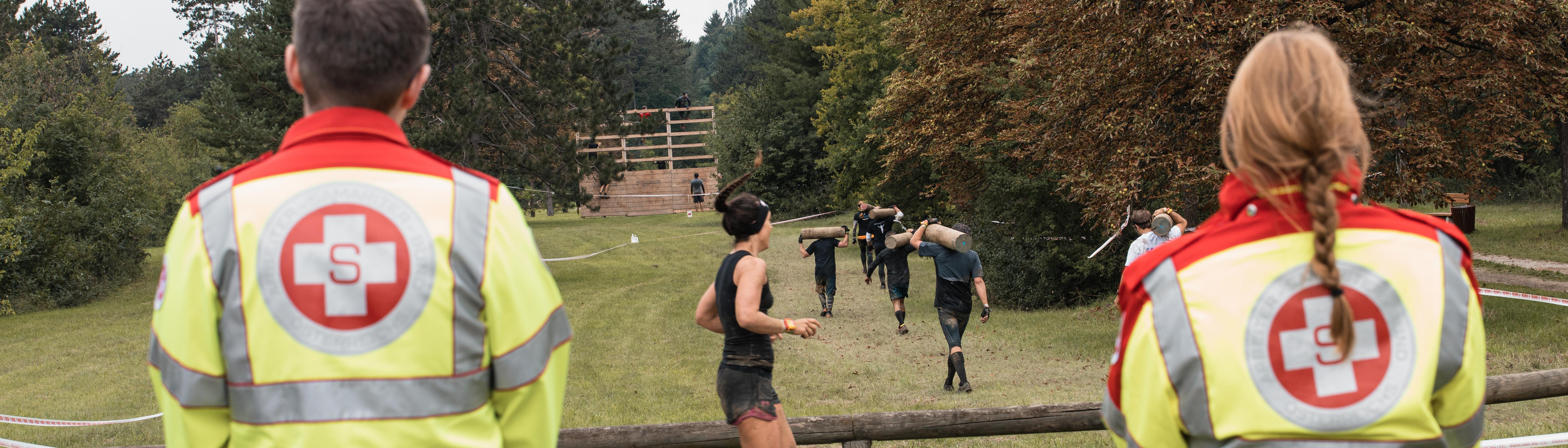 Sportler beim Spartan Race, Samariter in Uniform im Vordergrund