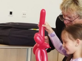 Ein Mädchen hält einen roten Ballon, während eine Erwachsene ihn präsentiert.