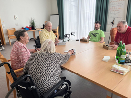 Fünf Personen sitzen an einem Tisch und spielen gemeinsam ein Spiel.