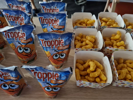 Tropfensäckchen mit orangefarbenem Getränk und Snacks in bunten Schalen.