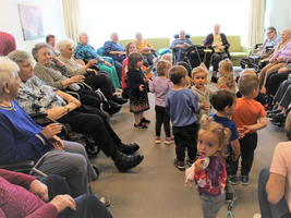 Kinder interagieren mit Senioren in einem gemeinsamen Raum.
