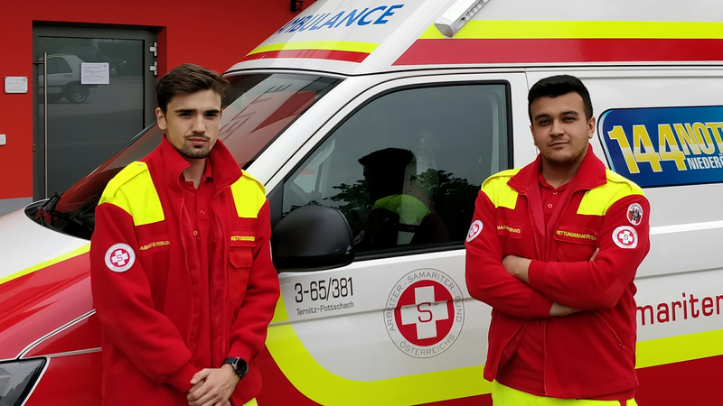 Zwei Rettungssanitäter stehen neben einem Krankenwagen.
