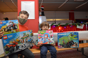 Zwei Kinder halten verschiedene Spielzeugboxen von LEGO und Playmobil in der Hand.