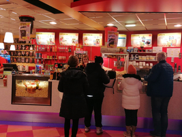 Popcornverkaufsstand mit Kunden, die Snacks und Getränke bestellen.