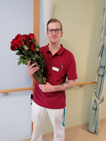 Ein Mann in rotem Shirt hält einen Strauß roter Rosen.