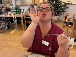 Frau mit Brille genießt ihr Essen und zeigt einen positiven Ausdruck.