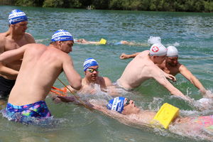 Schwimmer unterstützen einen in Not geratenen Teilnehmer im Wasser.