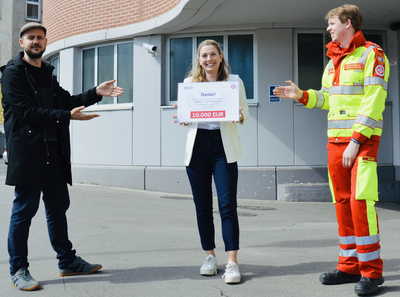 Eine Frau hält einen Scheck über 10.000 Euro und bedankt sich.