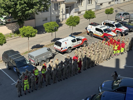 Eine Gruppe von Einsatzkräften steht in Uniform auf einem Parkplatz.