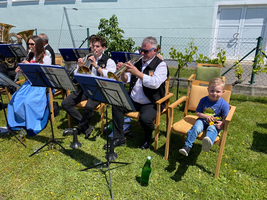 Eine Gruppe von Musikern spielt im Freien, während ein Kind zusieht.