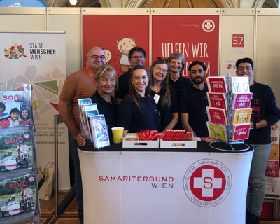Gruppe von Ehrenamtlichen auf Messe hinter Pult mit Samariterbund Wien Logo