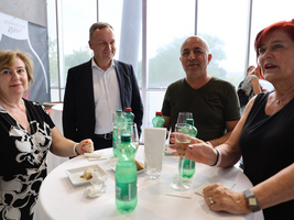Vier Personen stehen an einem Stehtisch und unterhalten sich bei einem Event.