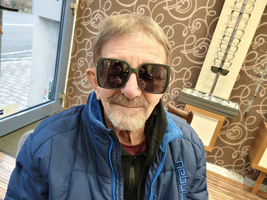 Ein älterer Mann trägt große Sonnenbrille und steht in einem Brillengeschäft.