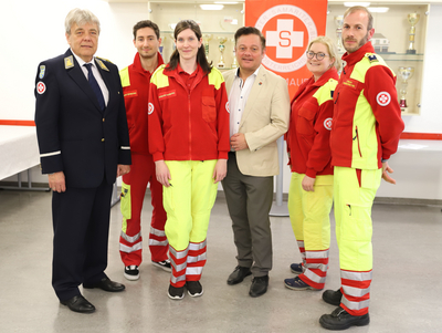 Sechs Personen in Rettungsdienstuniformen posieren zusammen in einem Innenraum.