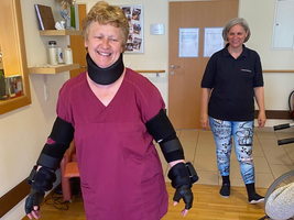 Eine lächelnde Frau trägt medizinische Schutzausrüstung in einem Raum.