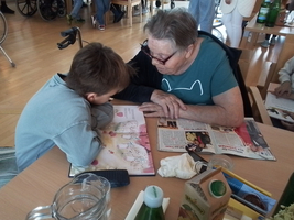 Ein Kind und eine ältere Dame betrachten gemeinsam ein Buch am Tisch.