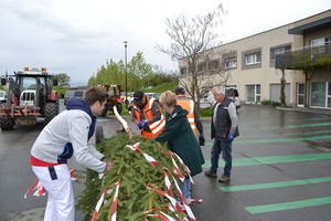 Eine Gruppe von Menschen dekoriert einen Baum mit Bändern im Freien.