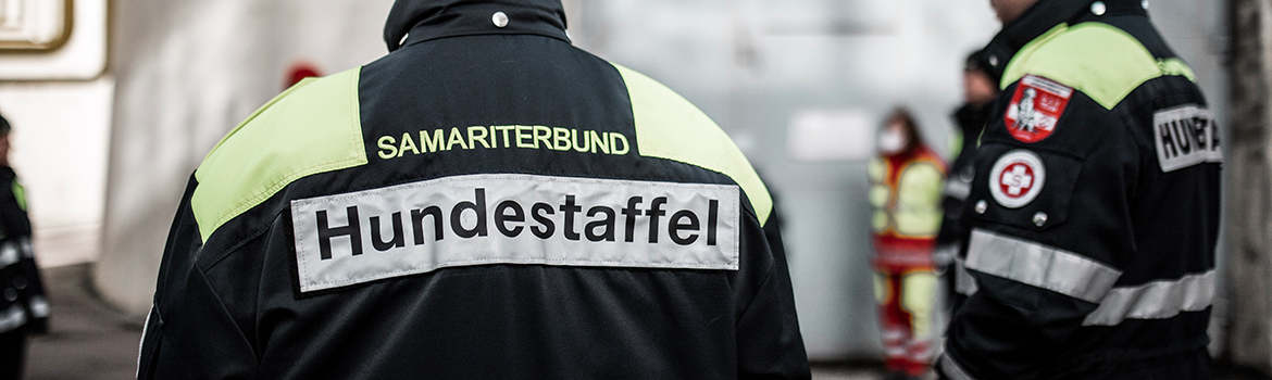 Rückansicht von Rettungskräften in Uniform mit der Aufschrift 