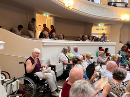 Eine Gruppe älterer Menschen sitzt im Zuschauerraum eines Theaters.