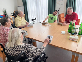 Fünf Personen sitzen an einem Tisch und spielen ein Spiel.