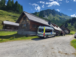 Ein Bauernhof mit Holzgebäuden in einer bergigen Landschaft.