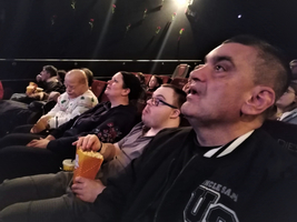 Gruppe von Menschen schaut gespannt einen Film im Kino. Snackboxen sind sichtbar.