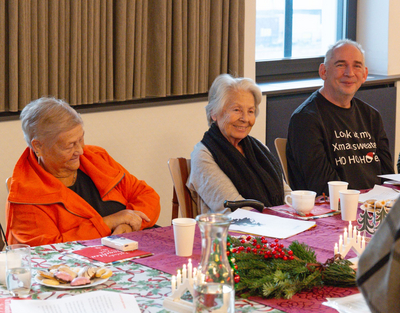 drei Senioren sitzen an einem gedeckten Weihnachtstisch, Weihnachtsfeier, Senioren-WGs