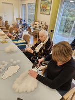 Senioren basteln mit Watte Wolken in einem gemütlichen Raum.