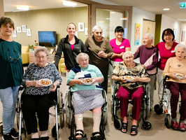 Gruppenfoto mit mehreren Frauen im Rollstuhl, die stolz ihre selbstgemachten Plätzchen halten.
