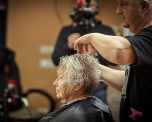 Detailaufnahme ältere Dame in Profilansicht, bekommt die Haare geschnitten, im Hintergrund Kamera