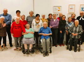 Gruppe von Menschen in einem Gemeinschaftsraum, versammelt um einen Tisch.