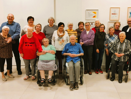 Gruppe von Menschen in einem Gemeinschaftsraum, versammelt um einen Tisch.