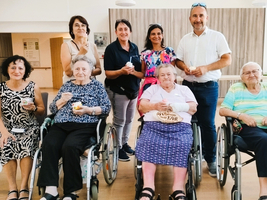 Gruppe von Senioren und Betreuern feiert mit Snacks in einem Gemeinschaftsraum.