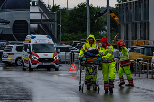 Rettungskräfte transportieren einen Patienten auf einer Trage bei Regen.