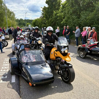 Motorradfahrer mit Beiwagen und Zuschauer bei einer Veranstaltung entlang der Straße.
