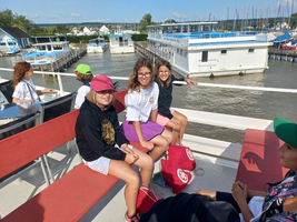 Vier Kinder sitzen auf einem Boot und lachen miteinander.