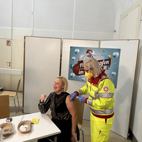 Eine Frau erhält eine Impfung von einer Fachkraft in Schutzkleidung.