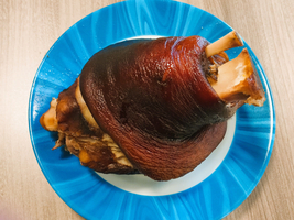 Ein gebratenes Schweinshaxen auf einem blauen Teller.