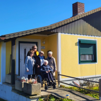 Veronika mit Familie vor Haus