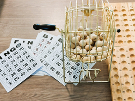 Eine Bingo-Kugelmaschine steht neben Bingo-Karten und einem Spielbrett.