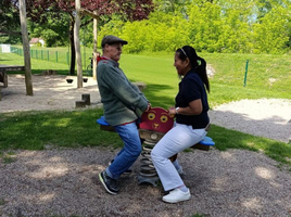Zwei Personen spielen fröhlich auf einem Wippgerät auf einem Spielplatz.